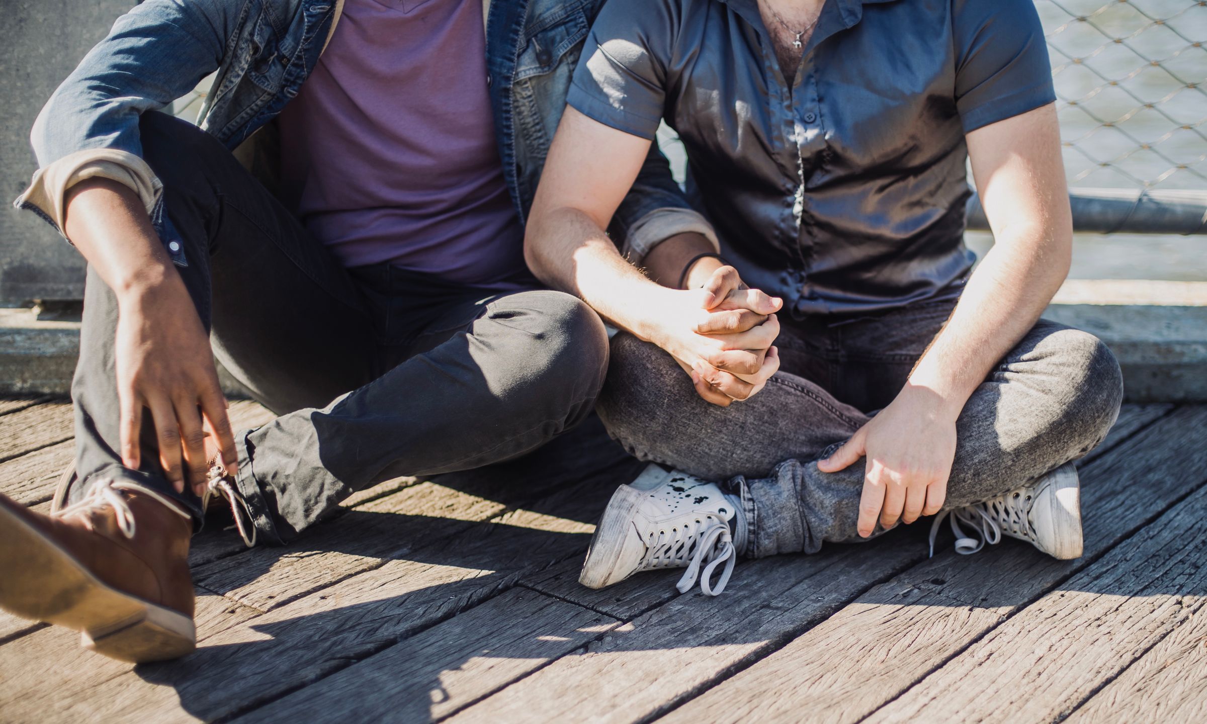 Twee mannen zitten hand in hand op een houten steiger